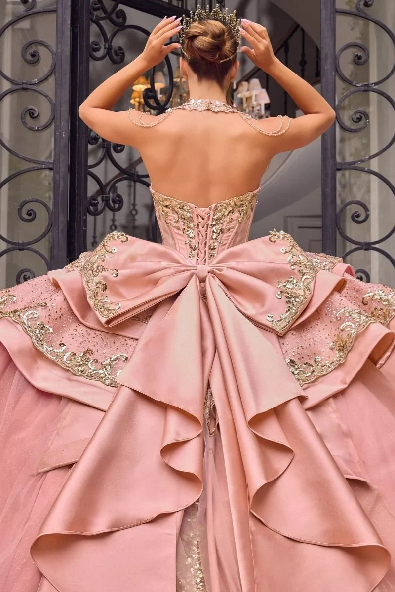Vestido de Quinceañera Ladivine rosa con pechera de pedrería, moño gigante y corona dorada.