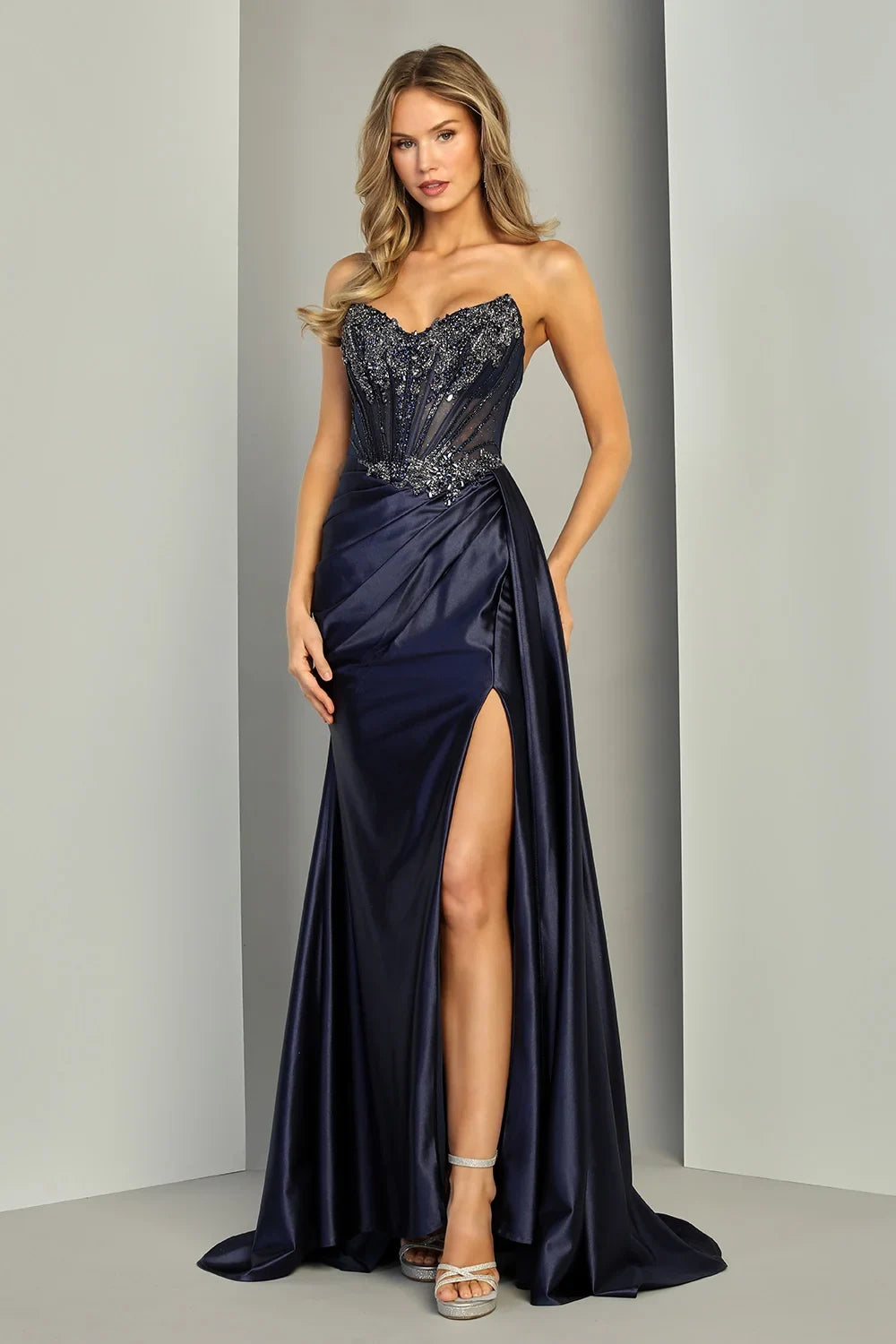 Vestido de gala strapless azul marino de Adora Design con corsé de pedrería y falda drapeada.