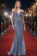 Mujer con vestido largo de gala gris plateado de encaje en alfombra roja, ideal para fiesta o evento elegante.