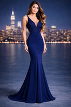 Mujer con vestido largo azul marino de noche, elegante, con encaje y escote, fondo urbano iluminado.