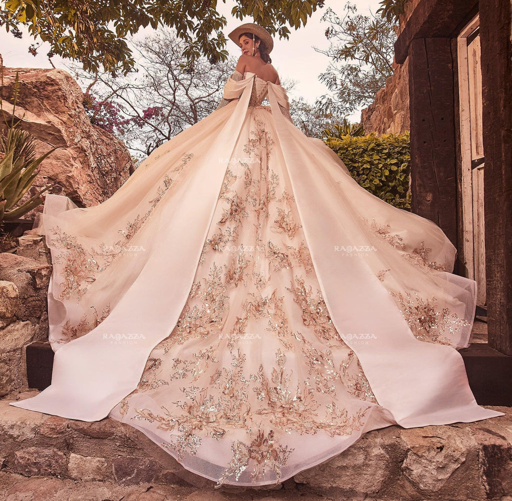 Vestido de novia con capa y bordados dorados, ideal para boda o XV años en entorno rústico