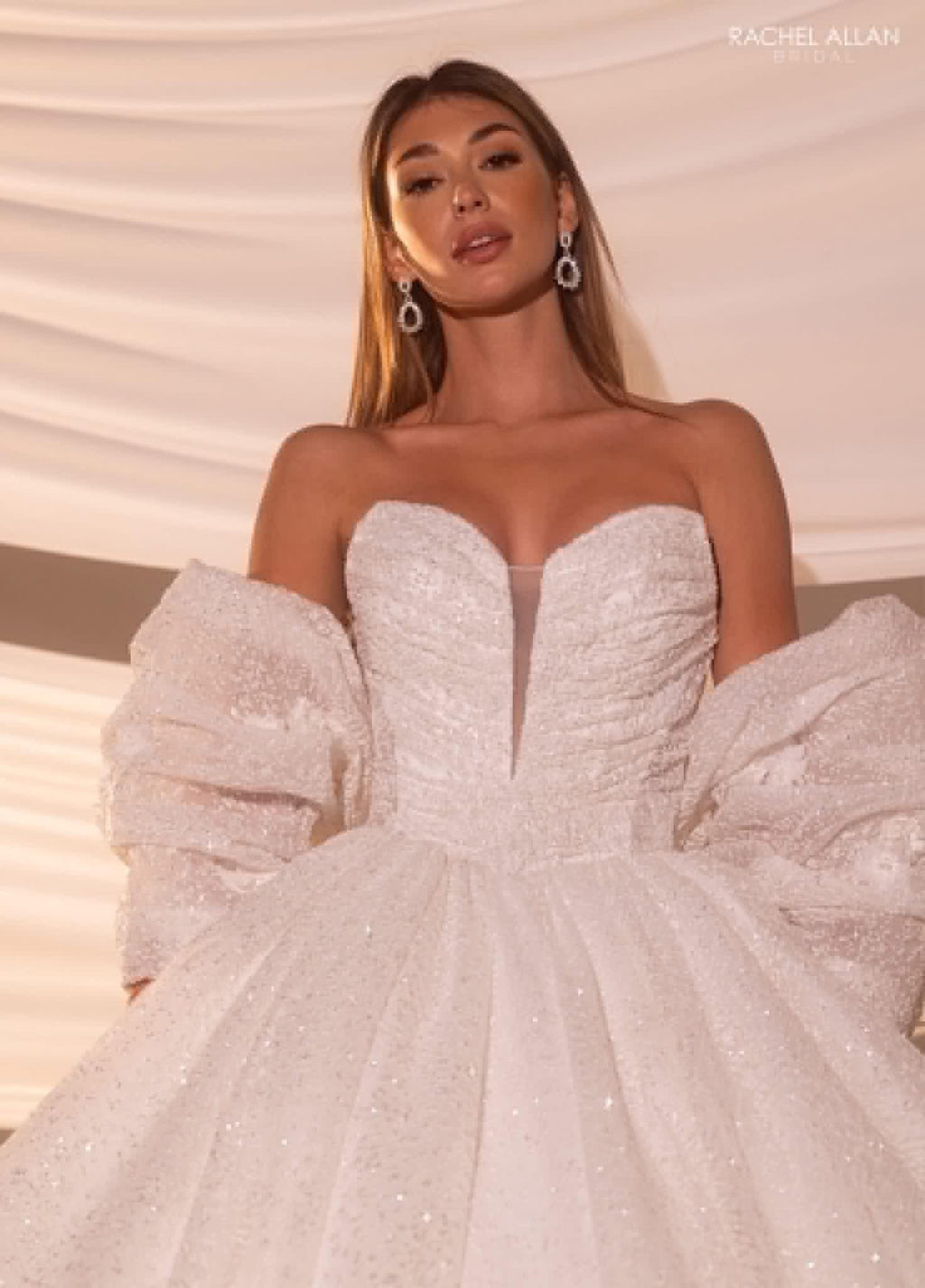 Mujer con vestido de novia blanco con mangas abullonadas y detalles brillantes, estilo elegante.