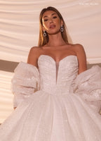 Mujer con vestido de novia blanco con mangas abullonadas y detalles brillantes, estilo elegante.