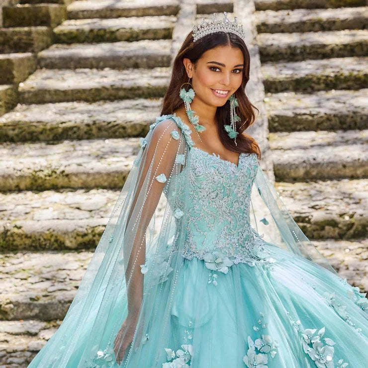 Joven con vestido de XV años azul celeste bordado, corona y aretes grandes en escalinata de piedra