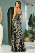 Mujer con vestido largo negro y dorado de fiesta, bordado floral, elegante, espalda descubierta.