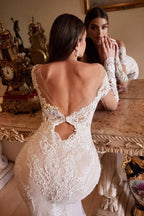 Mujer con vestido de novia de encaje blanco, espalda descubierta, frente a un espejo antiguo