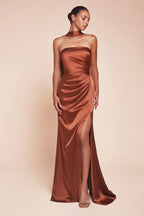 Mujer con vestido de fiesta satinado color cobre, escote strapless y abertura lateral elegante.