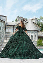 Joven con vestido de quinceañera verde esmeralda brillante y corona, posando frente a mansión elegante.