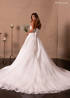 Mujer con vestido de novia blanco largo y cola, sosteniendo ramo, fondo elegante con velas.