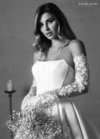 Mujer con vestido de novia blanco de manga larga con encaje floral y ramo de flores, fondo elegante.