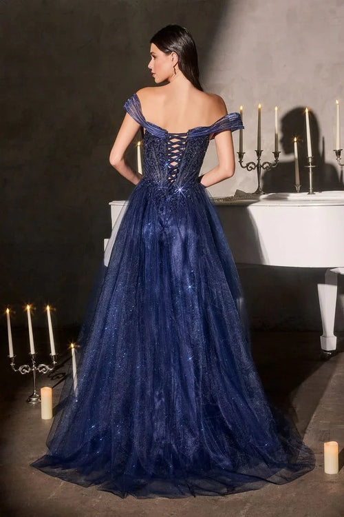 Mujer con vestido de gala azul marino brilloso, espalda descubierta, junto a candelabros y piano blanco.