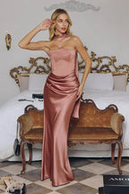Mujer con vestido largo satinado color rosa, elegante, ideal para fiesta o boda, en habitación lujosa.