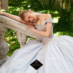 Joven con vestido de quinceañera azul claro brillante, detalles de pedrería, estilo princesa, posando en escalera de piedra, rodeada de vegetación.