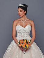 Novia con vestido DeKlaire Bridal corte línea A con encaje, perlas y ramo de rosas naranjas.
