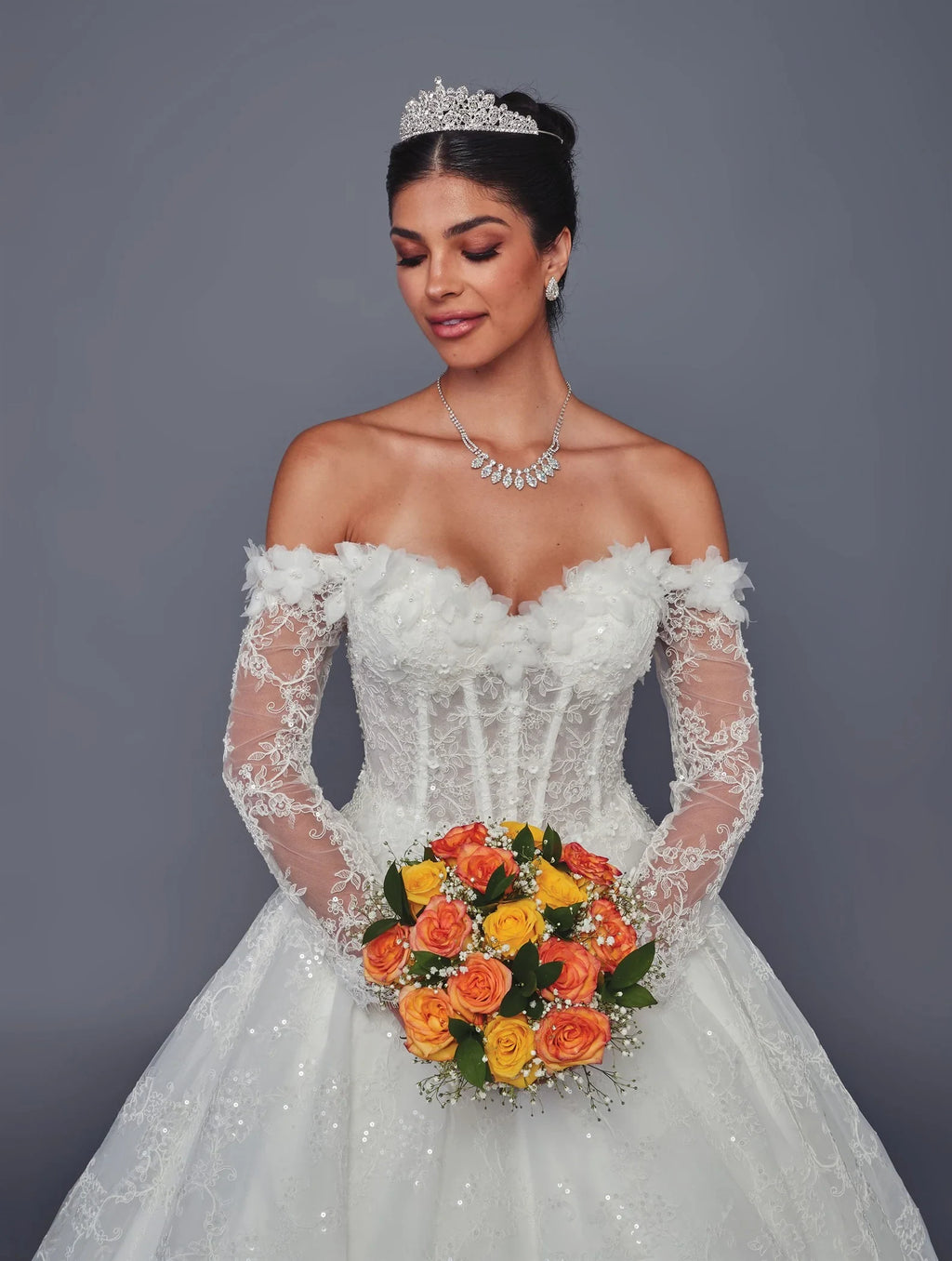 Novia con vestido DeKlaire Bridal corte línea A, escote corazón, mangas largas y ramo naranja.