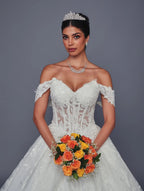 Novia con vestido de encaje línea A de DeKlaire Bridal, tiara y ramo de rosas naranjas.
