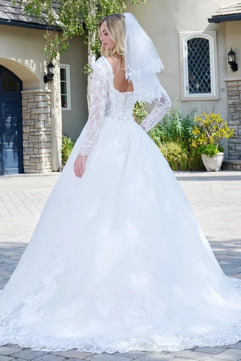 Vestido de novia blanco con mangas largas de encaje, cola amplia y velo bordado en jardín elegante.