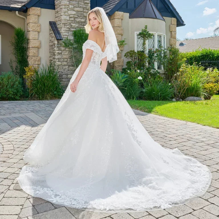 Vestido de novia corte princesa, escote en V y hombros caídos, con detalles de encaje y brillo.