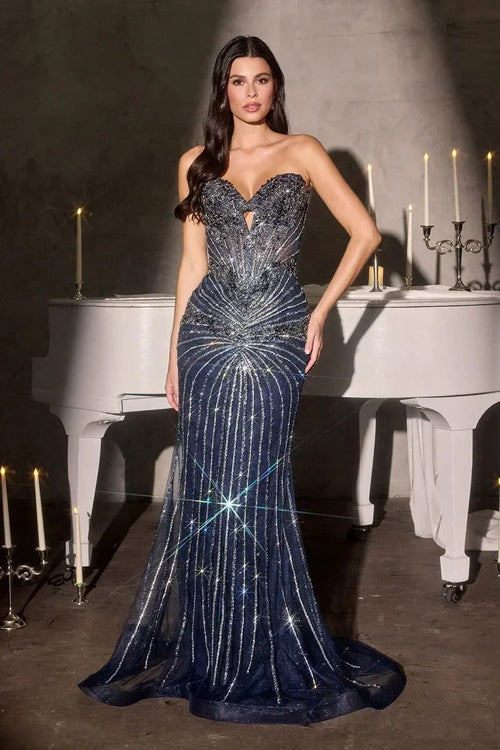 Vestido de noche azul marino con pedrería, escote corazón y fondo elegante con piano blanco.