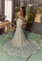 Vestido de novia blanco con encaje, espalda descubierta y cola larga bordada.