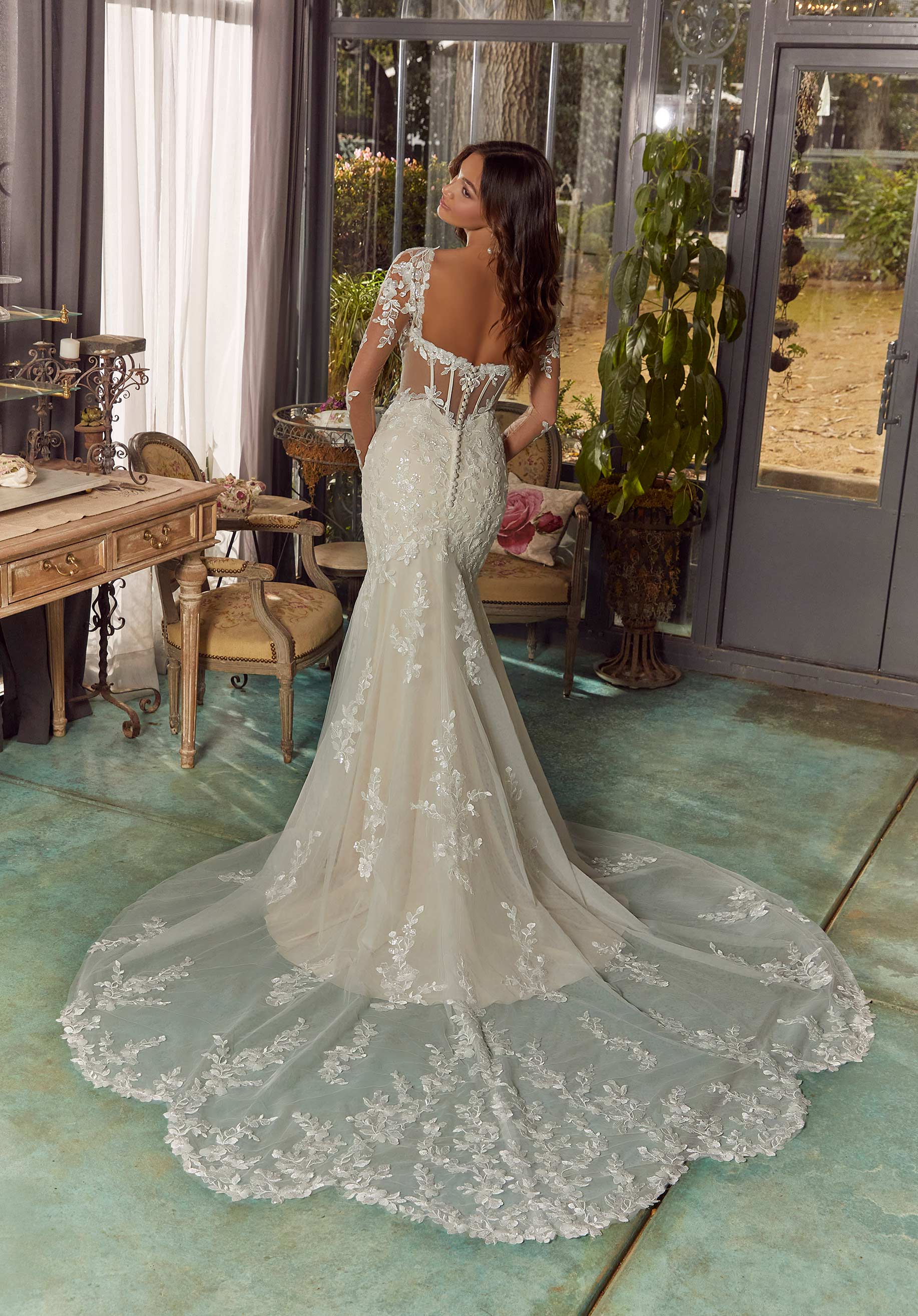 Vestido de novia blanco con encaje, espalda descubierta y cola larga bordada.