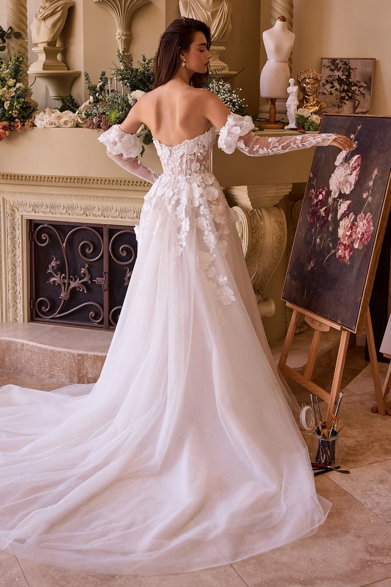 Novia de espalda con vestido blanco brillante, aplicaciones florales y guantes de encaje.