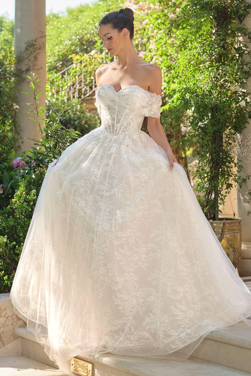 Vestido de novia blanco con escote corazón y encaje elegante en un jardín al aire libre.