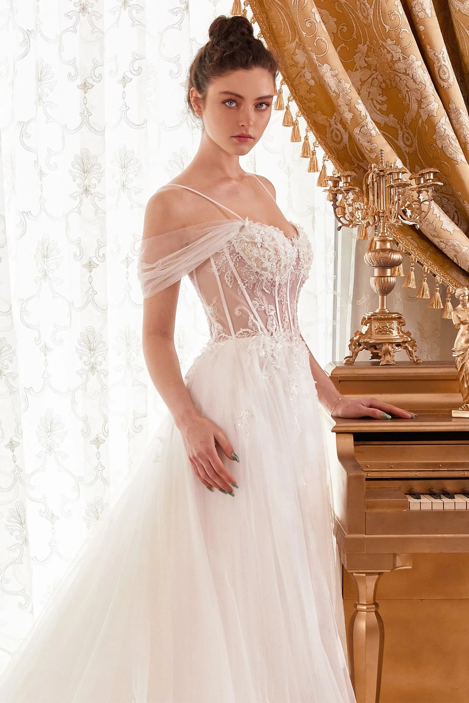 Mujer con vestido de novia blanco elegante, detalles florales, junto a piano dorado.